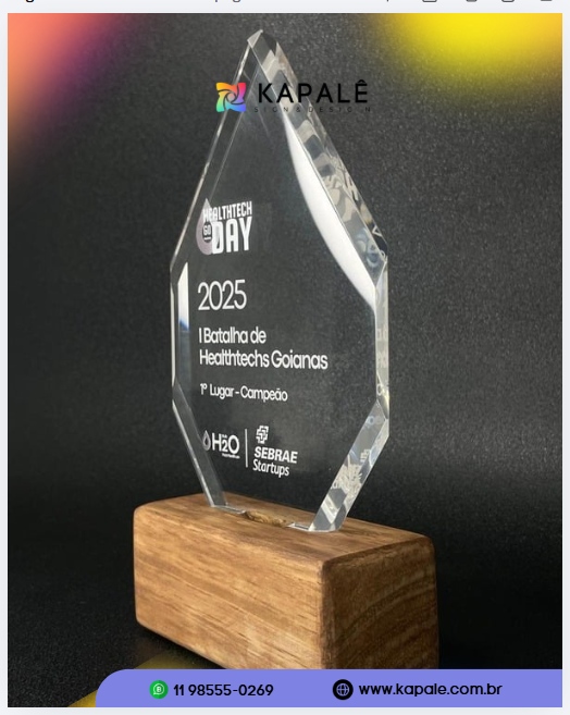 Troféu facetado transparente Healthtech Go Day 2025 sobre base quadrada de madeira